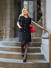 a lady wears a black single-breasted mini dress with black loafers